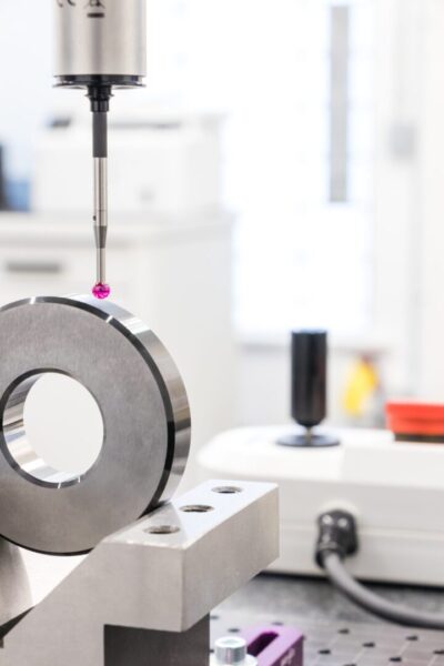 Coordinate measuring machine probing precision metal component in quality control laboratory